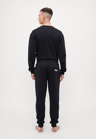 Black sweatshirt and matching joggers made of soft fabric. Features a logo patch on the back pocket and ribbed cuffs.