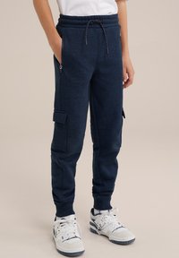 Pantalons de jogging bleu marine en tissu texturé, dotés d'une taille élastique avec cordon de serrage, de poches latérales et d'une poche cargo sur le côté.