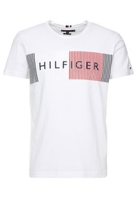 Bílý bavlněný T-shirt s grafickým designem červených a námořnických pruhů a textem "HILFIGER" tučnými černými písmeny přes hruď.