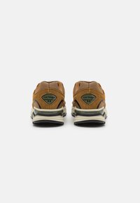 Brune ruskindssneakers med mesh-paneler, en robust sål og forstærket hæl. Har branding på hælen og en tekstureret finish.
