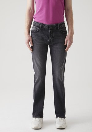 Svarta denimjeans med rak passform, utrustade med fem fickor och en blekt yta, tillsammans med en enkel rosa t-shirt och vita sneakers.