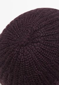 Berretto lavorato a maglia in viola scuro. Tessuto strutturato con un motivo a coste. Forma arrotondata con una parte superiore liscia e una sensazione morbida e calda.