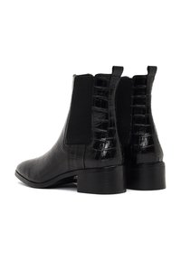 Botas tobilleras de cuero sintético negro con un patrón de cocodrilo, paneles laterales elásticos y punta cuadrada. El tacón bajo proporciona estabilidad.