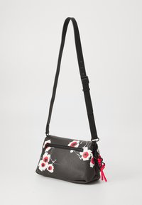 Borsa a tracolla in pelle nera con tasca con zip, caratterizzata da una stampa floreale rossa e bianca, tracolla regolabile e dettaglio con nappina rossa.