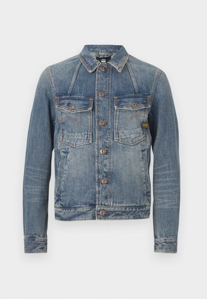 Blue denim jacket with brown buttons, two buttoned chest pockets, and visible stitching on sleeves and front panels.