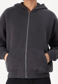 Donkergrijze zip-up hoodie met een voorrits, twee zijzakken, ribgebreide manchetten en zoom, en een ruime capuchon voor comfort.