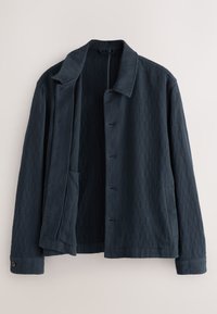 Marineblå tekstureret jakke med lodrette ribber, en spredt krave, knapper foran og en sidelomme. Stoffet har et blødt udseende.