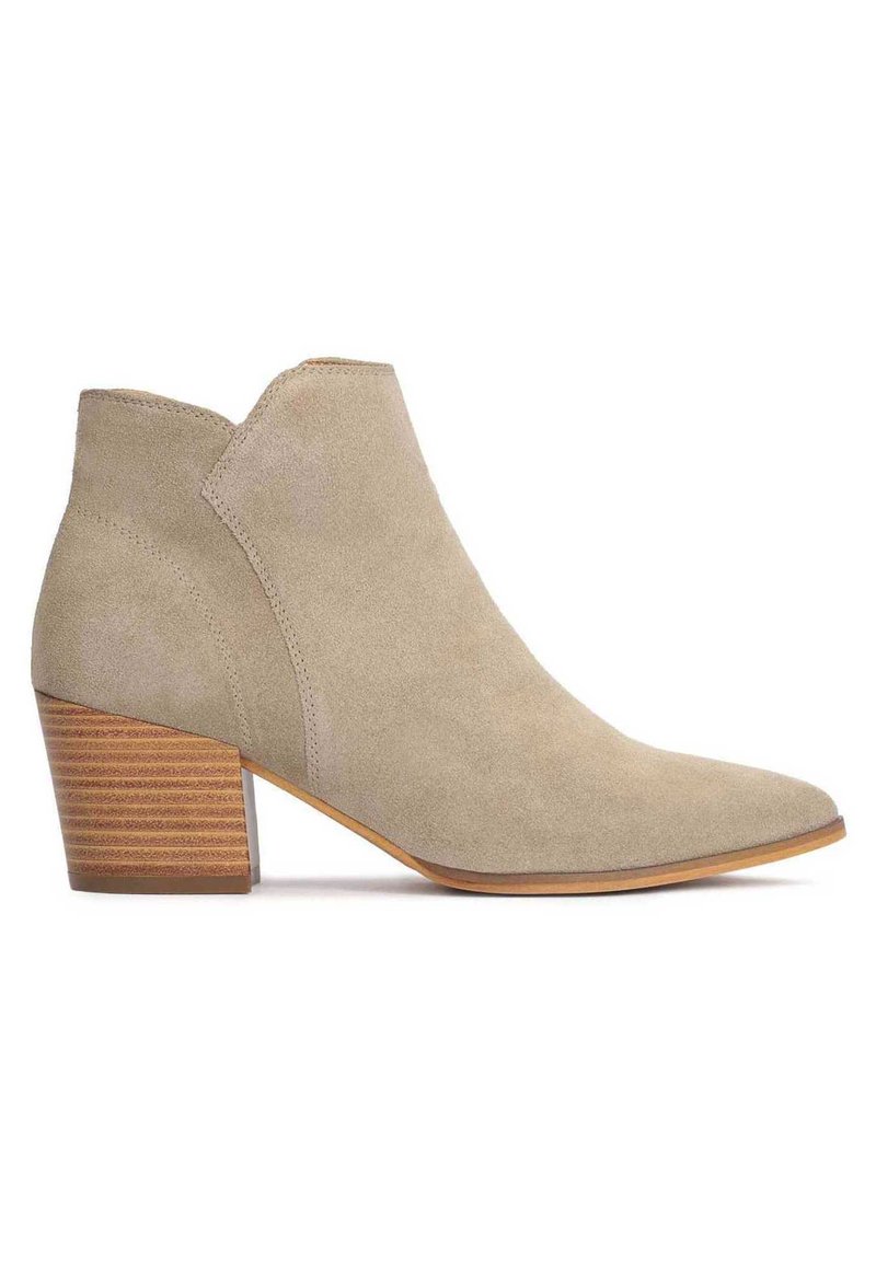 Botine din suede bej, cu vârf ascuțit și toc mediu cu efect de moloz. Prezintă un design decupat și o textură netedă.