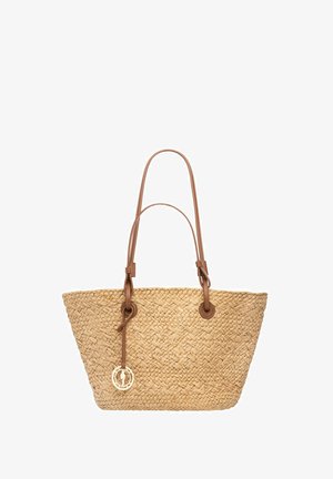 Tkana słomiana torba na ramię z dwoma jasnobrązowymi skórzanymi uchwytami i skórzanym paskiem trzymającym z przodu okrągły złoty wisiorek.