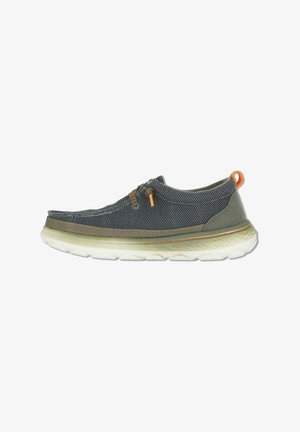 Zapato casual para hombre tipo slip-on con tejido de malla gris, detalles en marrón claro, suela blanca acolchada y lengüeta naranja en el talón.