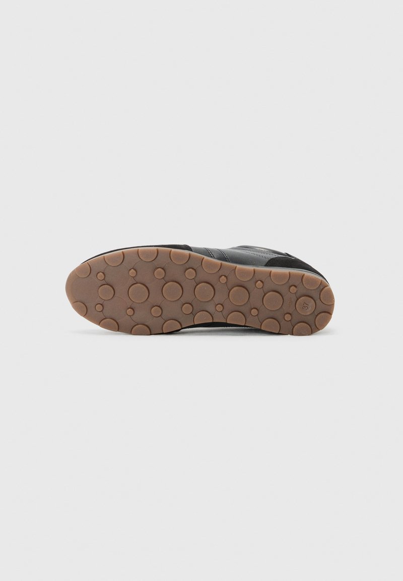 Semelle de sneaker noire avec une surface texturée, présentant un motif de grips circulaires. Couleur de base marron clair, en matériau caoutchouc.