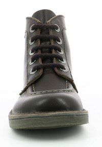 Bruine leren enkelboot met ronde neus, zes vetersleuven, contrasterende stiksels en een platte rubberen zool. De textuur is glad met subtiele accenten.
