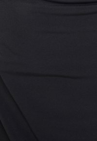 Tissu extensible noir, texture lisse, coupe ajustée avec un léger drapé. Finition sans coutures apparentes, sans éléments ou accessoires visibles.