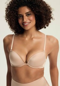 Delikatnie wyściełany, gładki biustonosz w beżowym kolorze z regulowanymi ramiączkami i niskim dekoltem. Posiada bezszwowe wykończenie dla wygody i wsparcia.