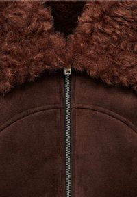 Brown suede jacket featuring a plush, curly brown fur collar and a silver zipper down the center. Smooth texture with rounded shoulder seams.