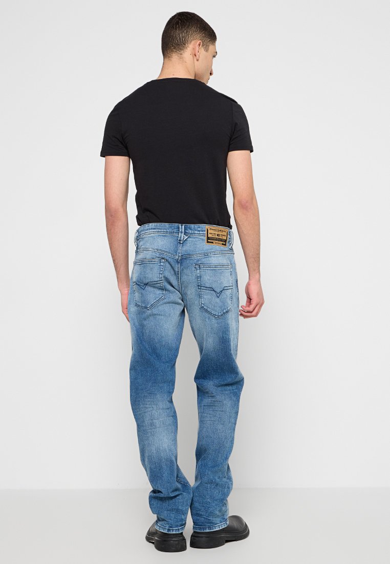 Jeans in denim blu chiaro con una vestibilità rilassata, dotati di due tasche posteriori e di un'etichetta in pelle marrone sulla vita. Indossata una t-shirt nera.