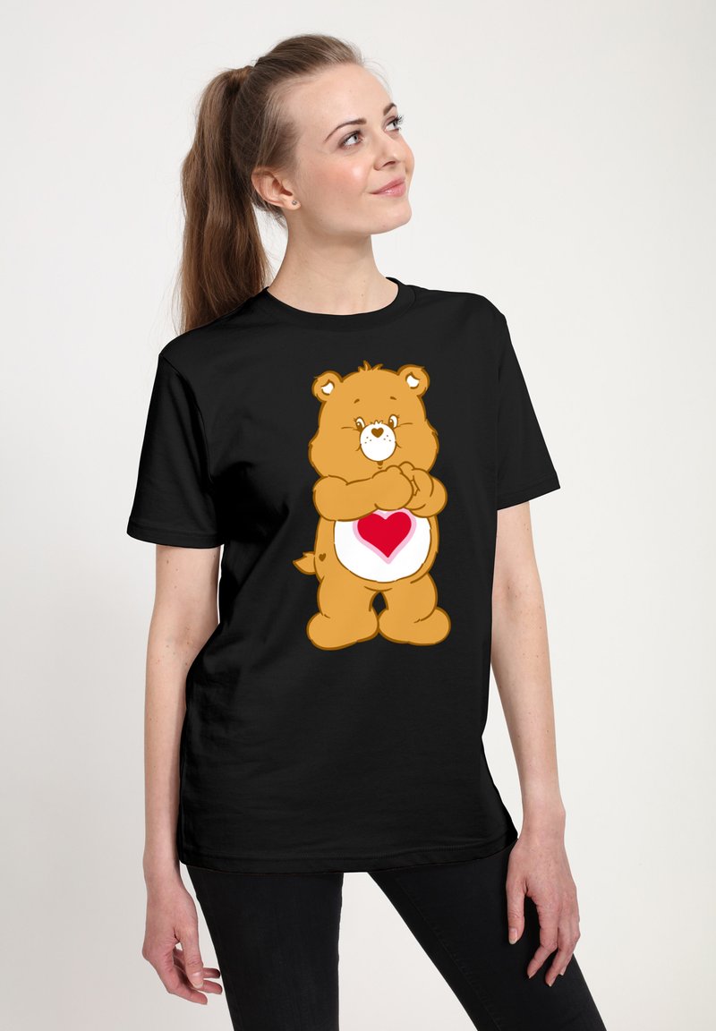Camiseta negra con un oso de dibujos animados que tiene un patrón de corazones en su vientre. El oso es marrón, con una cara y acentos de color crema.