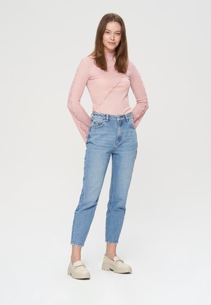 Maglietta a maniche lunghe ribbed rosa chiaro con cuciture testurizzate, abbinata a jeans in denim azzurro chiaro a vita alta e mocassini bianchi massicci.