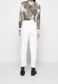 Bílé denimové kalhoty s volným střihem, s mírně obroušeným lemem. V kombinaci s dlouhým rukávem s šedým květinovým vzorem.