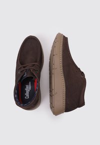 Chaussures en cuir marron avec une finition texturée, bout arrondi et semelle en caoutchouc. Présentent des lacets et une doublure intérieure à motif en bleu marine et rouge.