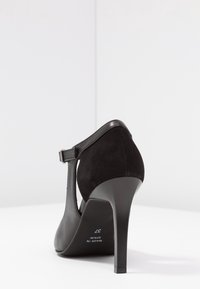 Černá lodička na vysokém podpatku se semišovým povrchem, kotníkovým páskem a špičatou špičkou. Podpatek je štíhlý a ve tvaru stiletto. Velikost 37.