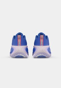 Ζευγάρι μπλέ αθλητικών παπουτσιών με ροζ λεπτομέρειες, που προβάλλονται από πίσω, δείχνοντας τις υφασμάτινες σόλες και την ετικέτα "Nike Running" στην ταμπέλα της φτέρνας.