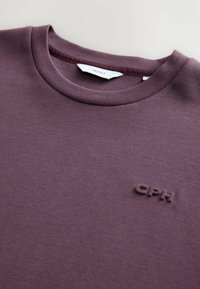 Lilla bomulds sweatshirt med rund halsudskæring og et tekstureret logo. Stoffet ser blødt ud med en glat, matFinish.