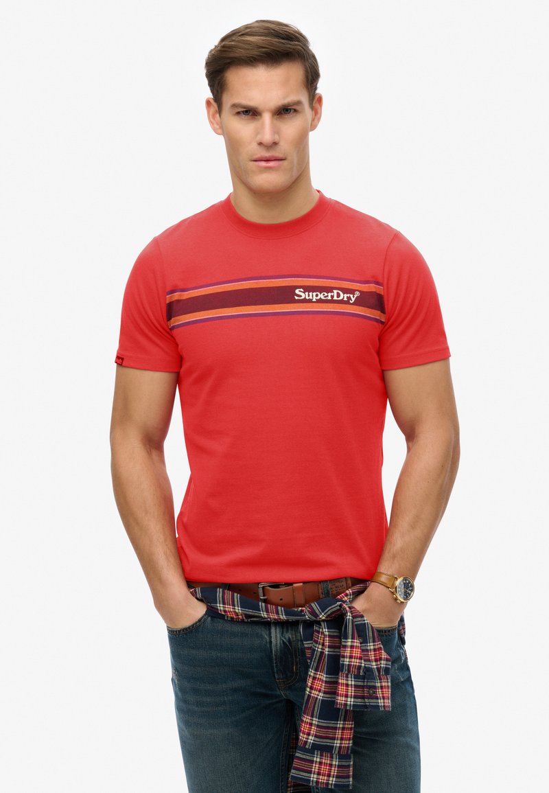 Rode katoenen t-shirt met een ronde hals, voorzien van horizontale strepen in paars en kastanjebruin. "SuperDry" logo gedrukt op de borst.