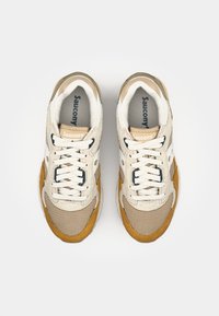 Beige and brown sneakers featuring a mesh upper, suede accents, and white laces. "Saucony" logo visible on the tongue and side.