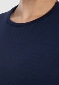 T-shirt aderente di colore blu navy con scollatura rotonda, realizzato in un tessuto liscio ed elastico. Design minimale senza motivi o accenti visibili.