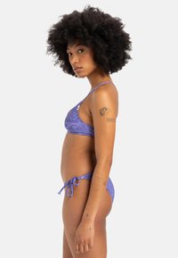 Lila Bikini aus strukturiertem Stoff mit geometrischem Muster, verstellbaren seitlichen Bindebändern und schlanken Spaghettiträgern.