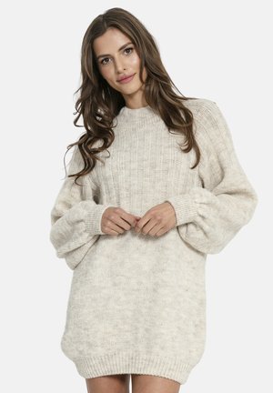 Jasno beżowa, oversize sukienka sweterkowa o ribbowanej teksturze, z długimi balonowymi rękawami i wysokim dekoltem, charakteryzująca się luźnym krojem i miękkim materiałem.