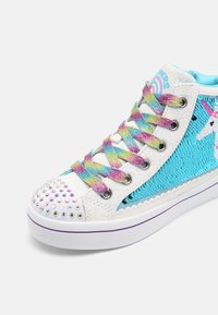 Höga sneakers med en glittrig vit ovandel, blå paljettaccenter, färgglada flätade snören och en nitar på tån.