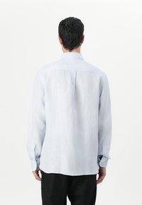 Ljust blå och vit randig skjorta med lång ärm, med en avslappnad passform, knäppningar vid ärmsluten och en pleat bak för extra komfort.