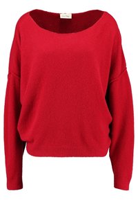 Röd oversized tröja gjord av ett mjukt, texturerat tyg. Har en bred halsringning, sänkta axlar och en ribbad nederkant för en avslappnad passform.