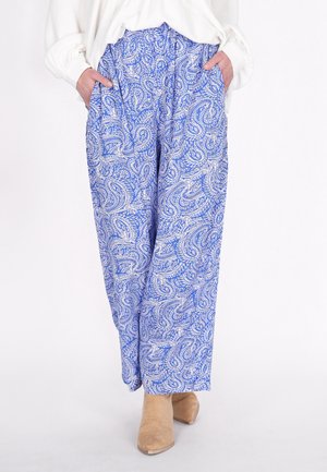 Pantaloni a palazzo blu con motivo paisley presentano una vita elastica e tasche laterali, realizzati in un tessuto leggero. Vengono indicate delle scarpe ankle in beige.