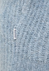 Jasnoniebieski sweter dziewiarski o miękkiej, puszystej fakturze i prążkowanym wykończeniu, z małą metką z napisem "MUSTANG".