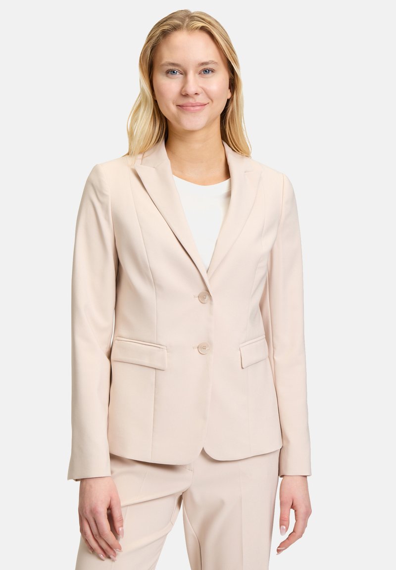 Ljusrosa skräddarsydd blazer med slag, två knappar, sidfickor och en mjuk textur, kombinerad med matchande byxor.