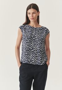 Jūrų ir baltos leopardų raštą turinti palaidinė su trumpomis rankovėmis, apvalia iškirpte ir laisvu siluetu, derinama su juodomis kelnėmis. Lygus audinio paviršius.