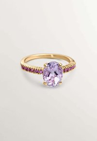 Anillo de oro con una gema ovalada de color lavanda, rodeada de pequeños detalles en rosa a lo largo de la banda, con superficies suaves y pulidas.