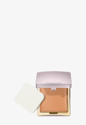 Poudre compacte pour maquillage de teinte beige, boîtier argenté ouvert, et une éponge applicatrice carrée blanche à côté.