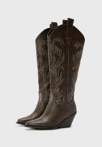 Hnědé kožené kovbojské boty s špičatými špičkami, klínovými podpatky a dekorativním prošíváním s květinovými vzory na holeni.