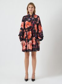 Czarna sukienka z pomarańczowym i czerwonym kwiatowym wzorem, długimi rękawami, kołnierzykiem oraz marszczeniem w talii. Noszona z czarnymi szpilkami.