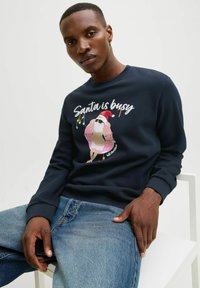 Navyblauwe sweatshirt met een graphic van een kerstman in zonnebril met een roze donut, versierd met kleurrijke lichtjes en de tekst "Kerstman is druk."