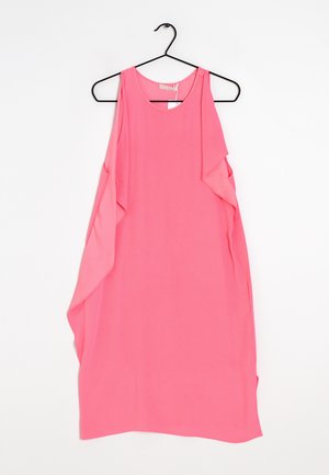 Robe sans manches rose vif avec des volants asymétriques sur le côté, accrochée à un cintre noir sur fond blanc.