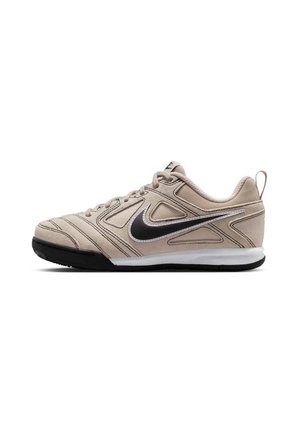 Baskets Nike beige avec logo Swoosh noir, semelle avant noire, semelle intermédiaire blanche, design à lacets et languette au talon.