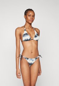 Dvojdielne bikiny so vzorom modro-bieleho tie-dye. Vrchná časť má trojuholníkové košíčky s nastaviteľnými šnúrkami a spodná časť má bočné šnúrky.