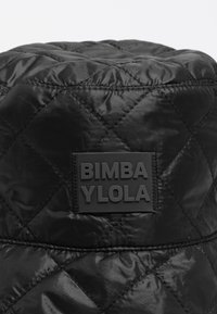 Czarny, pikowany kapelusz typu bucket wykonany z błyszczącej tkaniny, z gumowaną naszywką z logo "BIMBA YLOLA" z przodu.