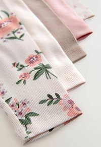 Samling av ribbade leggings i pastellfärger. Mönstren inkluderar blommönster i rosa, grönt och lila på en vit bas.