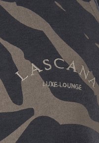 Měkká tkanina s maskáčovým vzorem v tmavě šedé a béžové barvě, s prošitým logem "LASCANA LUXE-LOUNGE" světlejší nití, s texturovaným povrchem.